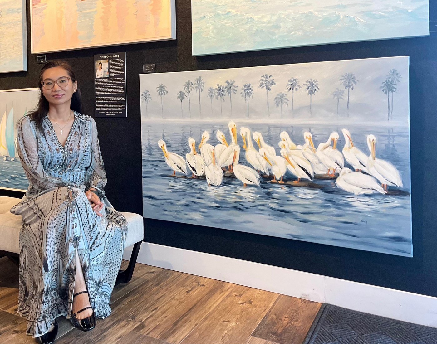 Qing Wang at a gallery exhibition beside her pelican painting